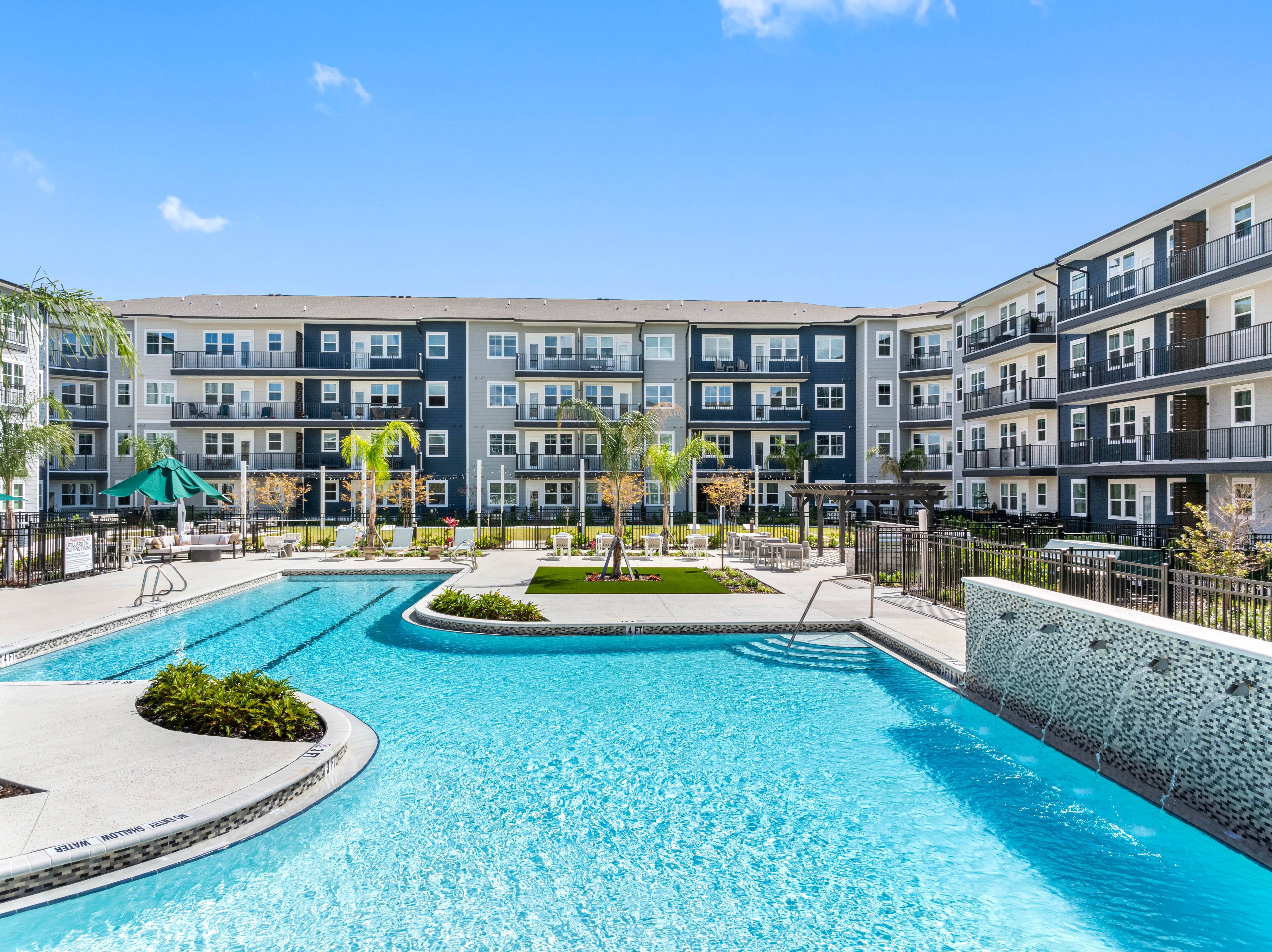 A large swimming pool in front of apartment buildings.